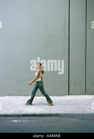 Donna camminando sul marciapiede, vista laterale Foto Stock
