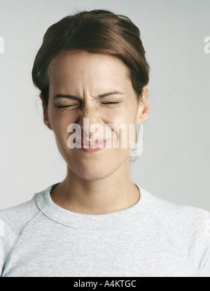Giovane donna spremitura di chiudere gli occhi, close-up Foto Stock