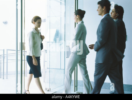 Gli imprenditori entrando e uscendo attraverso delle porte in vetro Foto Stock