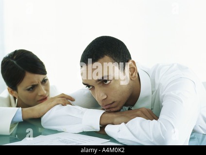 L'uomo con la testa rivolta verso il basso sulla tabella, donne toccando il suo braccio che guardano a lui con preoccupazione Foto Stock