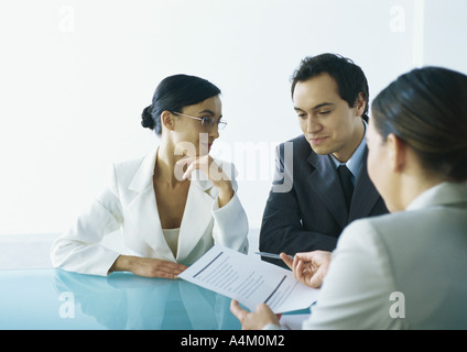 Imprenditore e imprenditrice seduta a tavola di fronte imprenditrice tenendo fuori il documento e penna Foto Stock