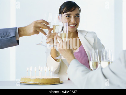 Gli imprenditori tintinnanti bicchieri di champagne sulla torta di compleanno Foto Stock