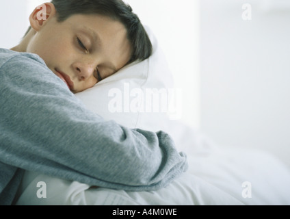 Ragazzo con gli occhi chiusi snuggling con cuscino Foto Stock