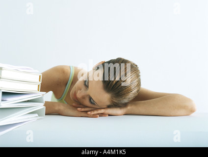 Donna che Dorme con la testa sulla scrivania accanto alla pila di cartelle Foto Stock