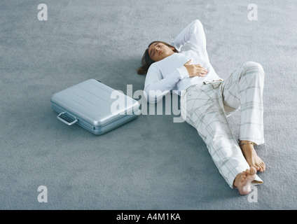 Uomo disteso su un tappeto accanto alla cartella Foto Stock