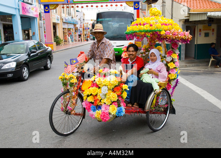 Un Malay famiglia musulmana di equitazione in un decorato in maniera colorata riscio' in Malacca Foto Stock