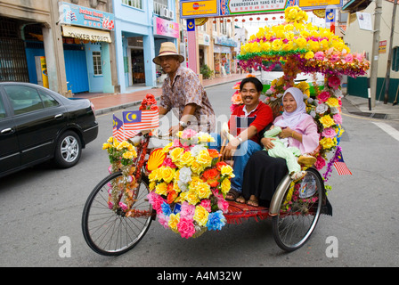 Un Malay famiglia musulmana di equitazione in un decorato in maniera colorata riscio' in Malacca Foto Stock