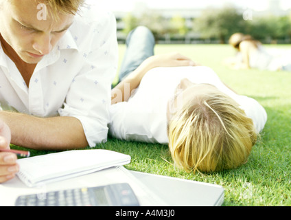 Gli studenti giacente su erba, giovane studiando, giovane donna sdraiata sulla schiena Foto Stock