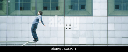 Giovane uomo in piedi precariamente su rampa flessione all'indietro Foto Stock