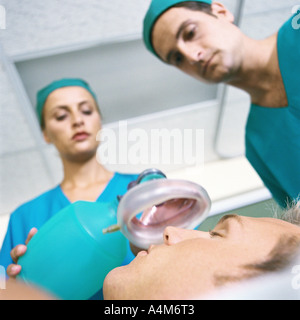 I medici ponendo le maschere di ossigeno oltre il viso del paziente Foto Stock