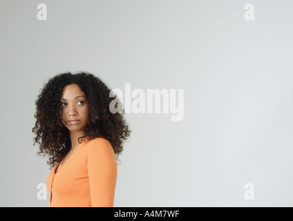 Giovane donna guardando sopra la spalla Foto Stock