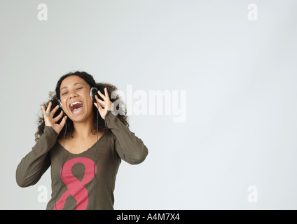 Giovane donna ascoltando le cuffie, cantando, ritratto Foto Stock