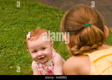 Due sorelle giocare all'aperto in estate il sole Foto Stock