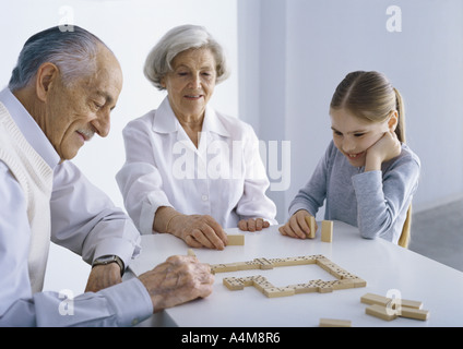 I nonni e la ragazza seduta al tavolo GIOCA Domino Foto Stock