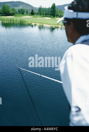 Il Golfer recupero palla in stagno con pole Foto Stock