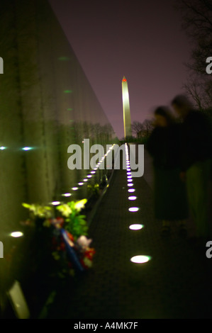 Giovane visiti il Viet Nam Memoriale di guerra durante la notte con il Monumento di Washington nella distanza Washington DC USA Foto Stock