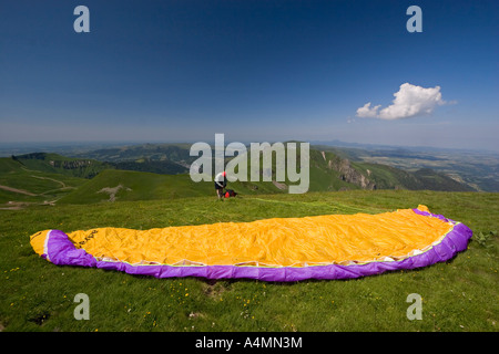 Un parapendio prepara il suo decollo oltre il massiccio del Sancy (Francia). Parapentiste préparant figlio envol dans le Massif du Sancy. Foto Stock