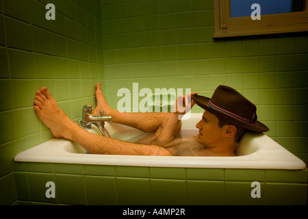 Un uomo con cappello peruviano avente una vasca da bagno. Homme coiffé d' onu chapeau Péruvien prenant onu bain. Foto Stock