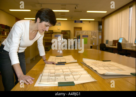 Signora guardando a casa e la strada dei piani nella pianificazione locale records office Foto Stock