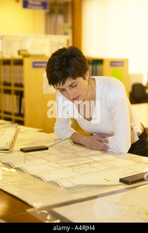 Signora guardando a casa e la strada dei piani nella pianificazione locale records office Foto Stock