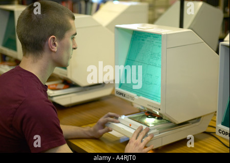 Giovane uomo studiando gli archivi di microfilm presso la locale county records office Lancashire England Regno Unito Foto Stock