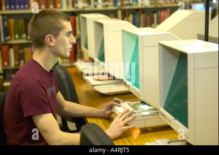 Giovane uomo studiando gli archivi di microfilm presso la locale county records office Lancashire England Regno Unito Foto Stock