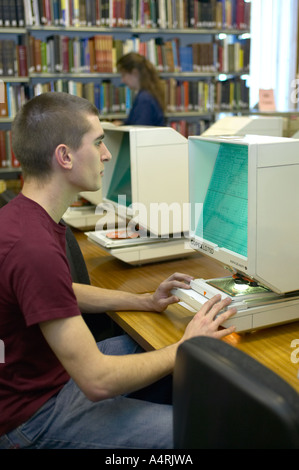 Giovane uomo studiando gli archivi di microfilm presso la locale county records office Lancashire England Regno Unito Foto Stock