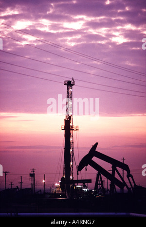 Impianti di trivellazione del petrolio e pumpjacks profilarsi in un campo petrolifero in California. Foto Stock