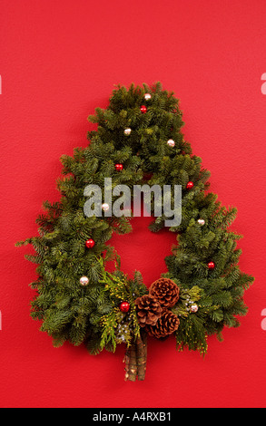 Albero di Natale a forma di corona sulla parete rossa Foto Stock