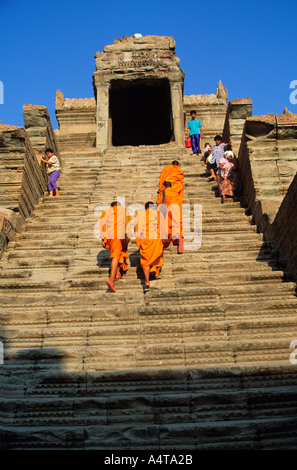 I monaci in abiti dello zafferano salendo i gradini superiori a Angkor Wat inCambodia come locale adoratori di venire giù Foto Stock