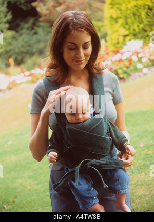 Madre che guarda il suo bambino figlio in un'imbragatura del bambino, Regno Unito Foto Stock