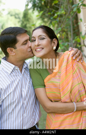 Uomo di baciare la sua madre sulla guancia all'aperto Foto Stock