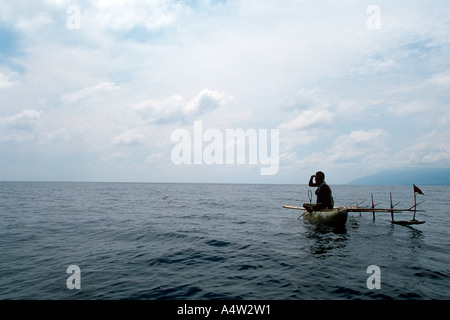 Robert uno squalo chiamante da Kontu villaggio sulla costa ovest della Nuova Irlanda scansiona l'orizzonte dal suo canoa per segni di squali Foto Stock