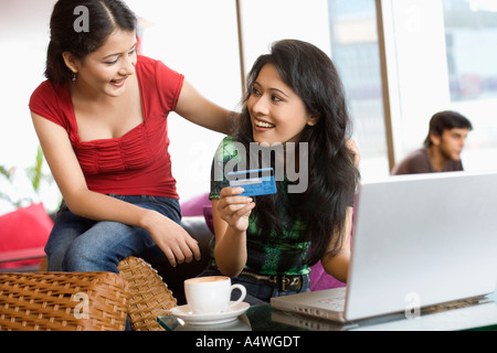 Le donne lo shopping online in cafe Foto Stock