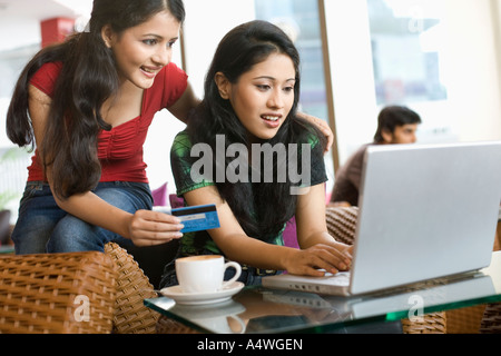 Le donne lo shopping online in cafe Foto Stock