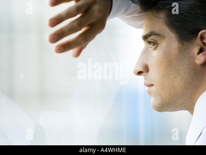 Uomo che guarda attraverso la finestra Foto Stock