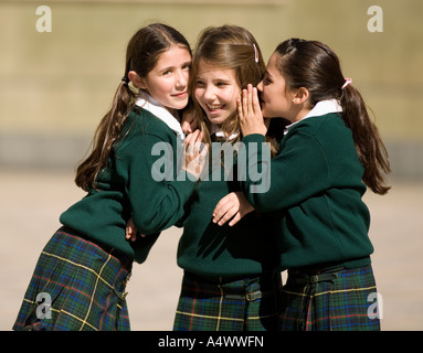 Giovani studenti whispering in cortile Foto Stock