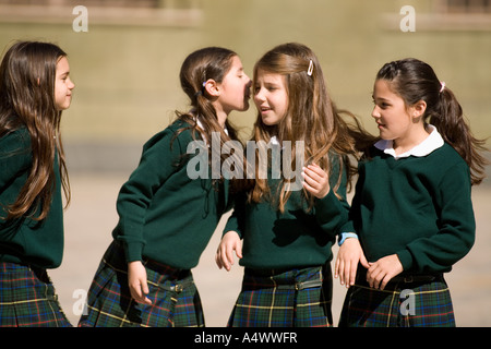 Giovani studenti whispering in cortile Foto Stock