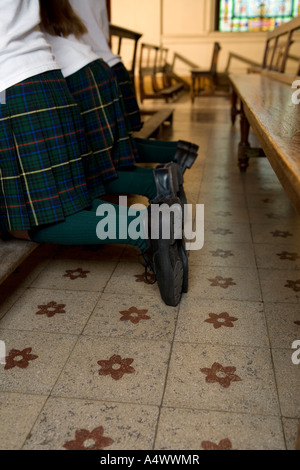 I giovani studenti in ginocchio in file di banchi in chiesa Foto Stock