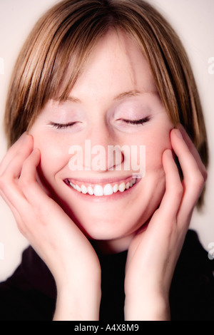 Giovane donna con gli occhi chiusi, sorridente, close-up Foto Stock