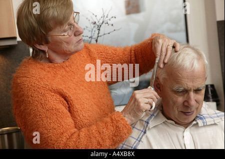 Vecchia donna tagli uomo vecchio i capelli Foto Stock