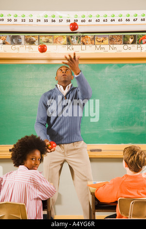 Insegnante di sesso maschile di mele di giocoleria in aula Foto Stock