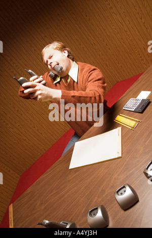 Imprenditore al desk utilizzando telefoni multipli Foto Stock