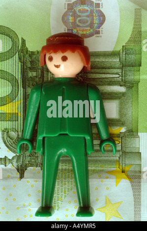 Tra banconote diverse figure (Playmobil) stand. 100 euro. Foto Stock