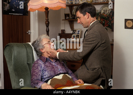 Medico su home visita esaminando le ghiandole di una signora anziana Foto Stock