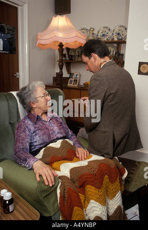 Medico su home visita tenendo la temperatura del paziente anziano Foto Stock
