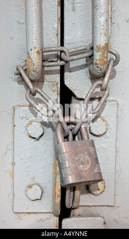 Le maniglie di una pesante porta di acciaio incatenati e bloccato con un lucchetto in Inghilterra Foto Stock