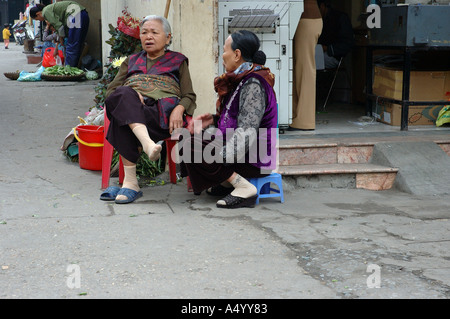 Due vecchie signore seduto a un angolo di strada avente una chat, Hanoi Vietnam. Foto Stock