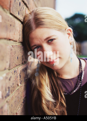 Ragazza appoggiata contro una parete Foto Stock