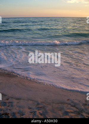 Sciabordare di onde sulla spiaggia al tramonto Foto Stock